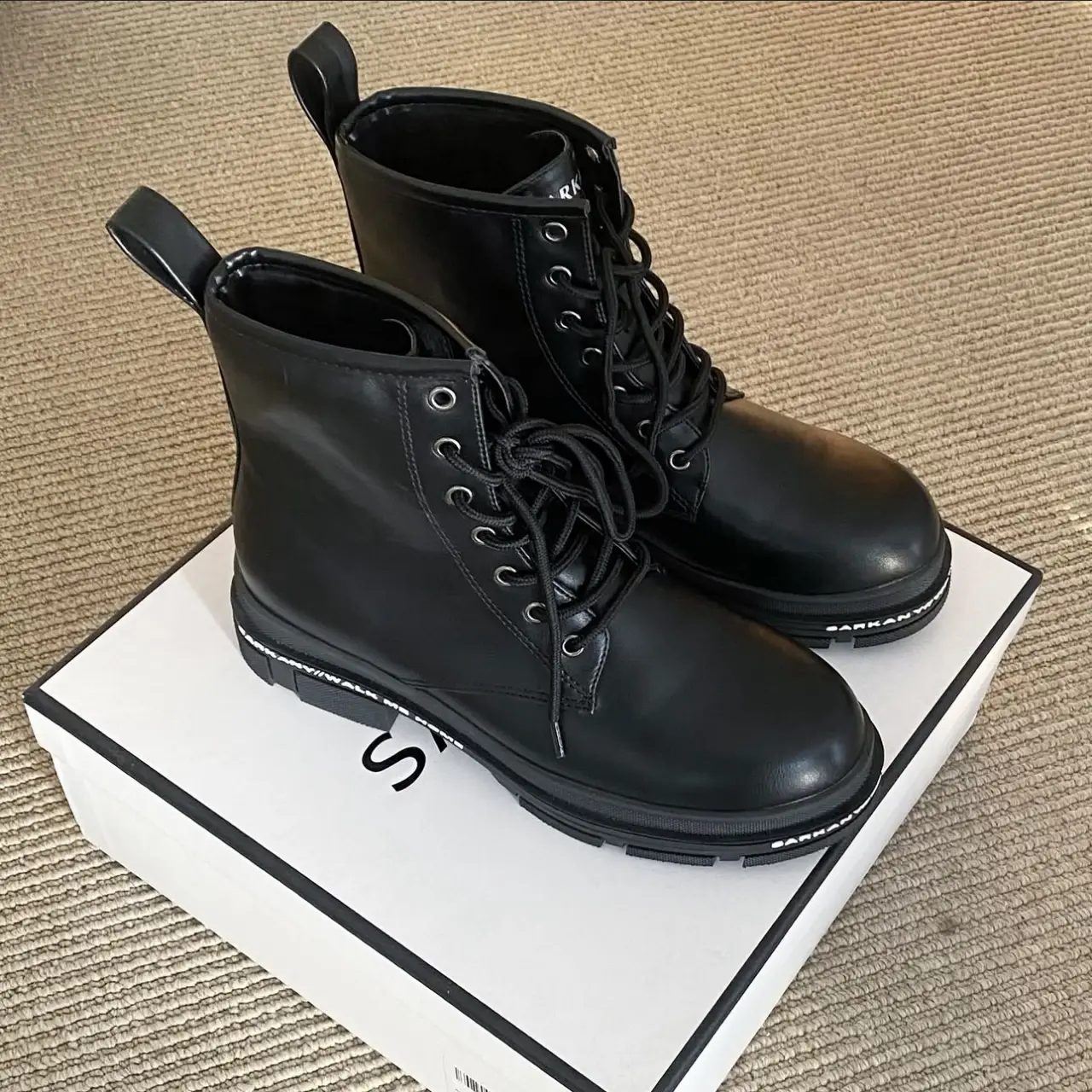 Borsegos negros de cuero sintético con cordones y suela gruesa. Ideales para un look urbano y moderno. Perfectos para combinar con jeans, faldas o vestidos. Cómodos y versátiles para cualquier ocasión.