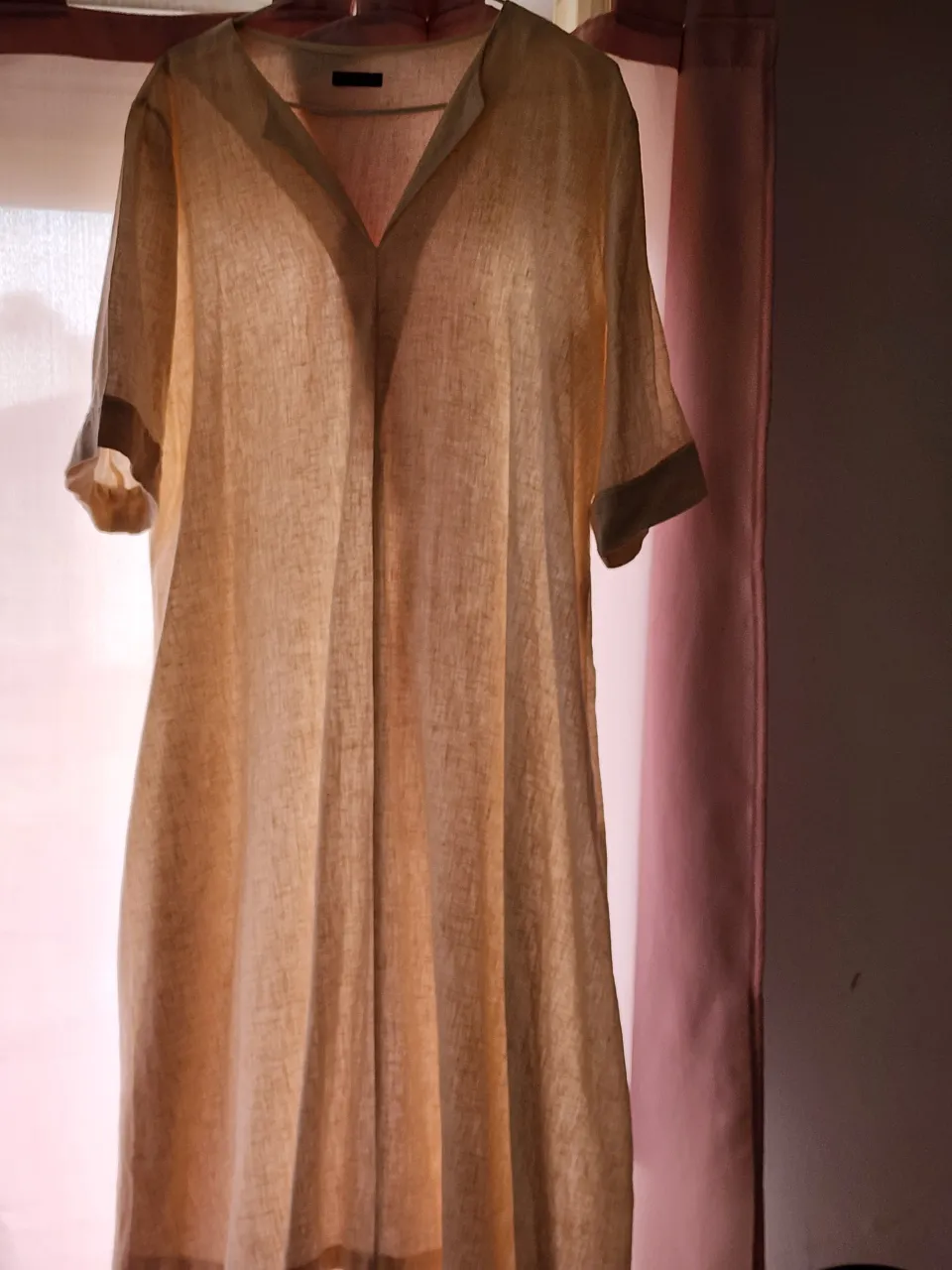 Remera de lino color crudo con cuello en V y mangas cortas. Tiene un detalle en las mangas y en el cuello.