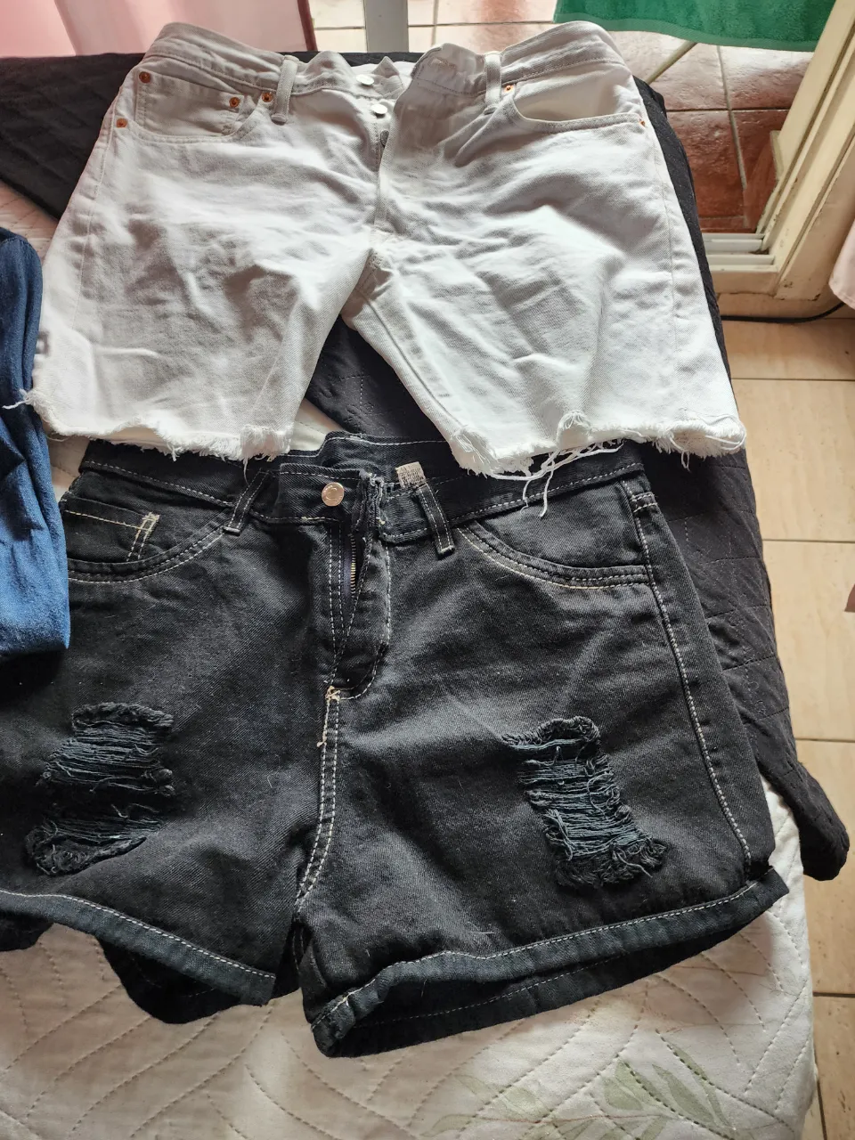 Shorts de jean blancos con roturas y terminación desflecada. Shorts de jean negros con roturas y terminación desflecada.