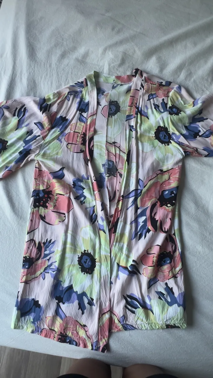 Kimono estampado con flores grandes en tonos rosas, azules, amarillos y verdes. Posee mangas anchas y es abierto al frente.