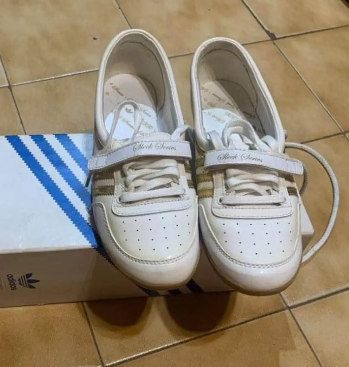 Zapatillas Adidas Sleek Series blancas con detalles dorados. Diseño clásico y elegante, ideales para un look casual y cómodo.
