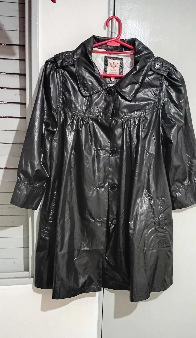 Impermeable negro brillante con botones y mangas 3/4. Ideal para la lluvia y un look elegante.