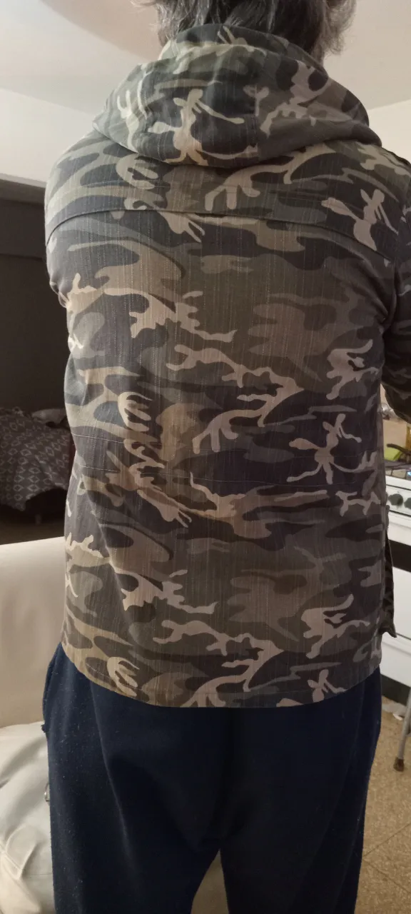 Buzo con capucha y cierre frontal, estampado camuflado en tonos verdes y marrones. Ideal para un look casual y urbano.