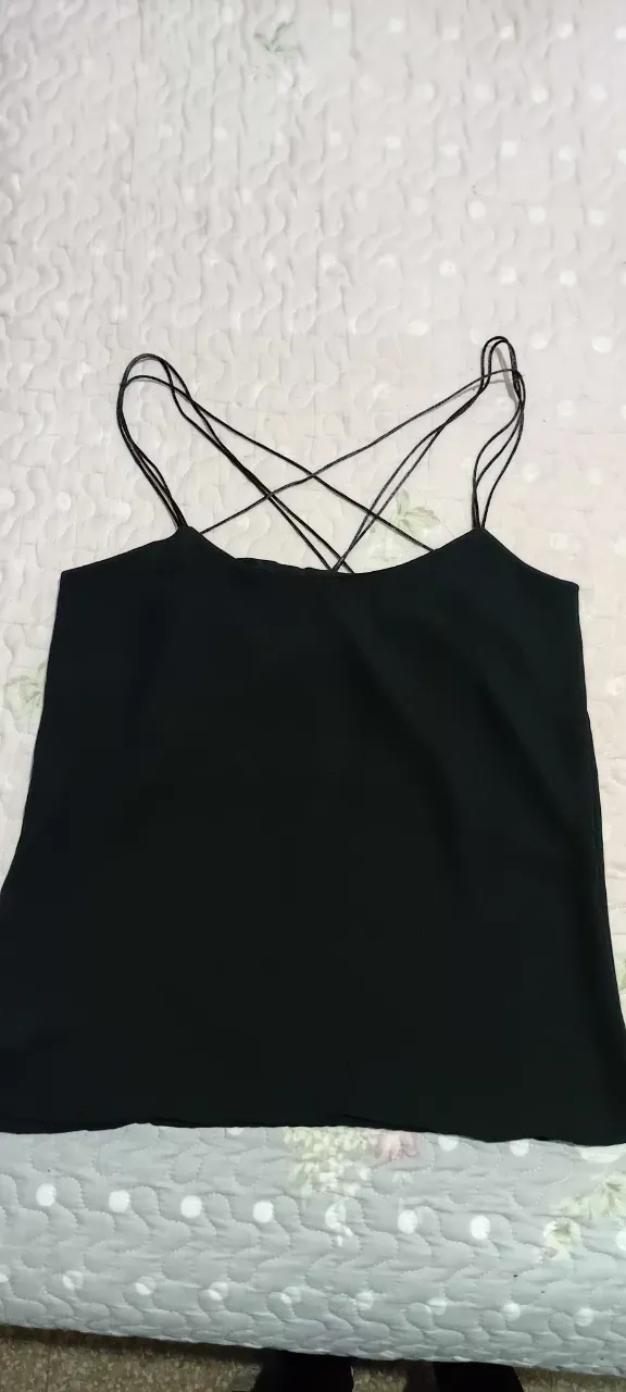 Top negro con tiras finas cruzadas en la espalda, ideal para un look moderno y versátil. Perfecto para combinar con jeans, faldas o pantalones de vestir.