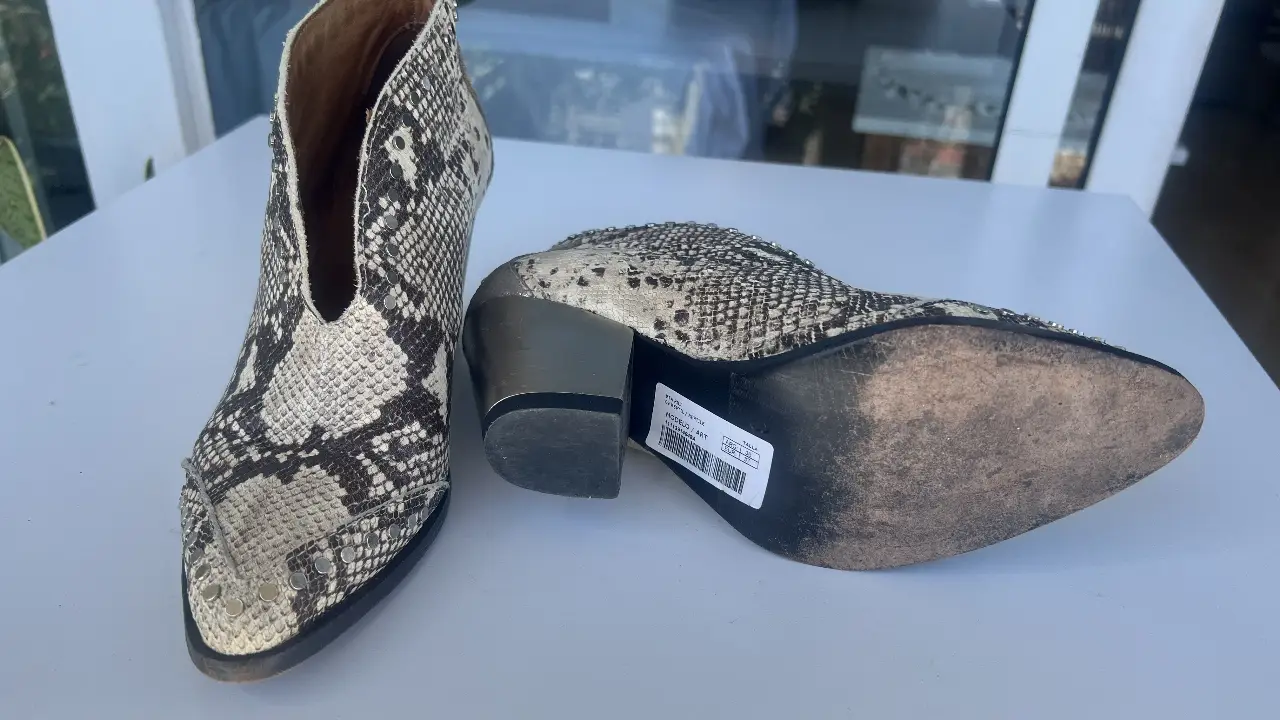 Botinetas de cuero con estampado de serpiente, detalles plateados y taco geométrico. Ideales para un look audaz y moderno.