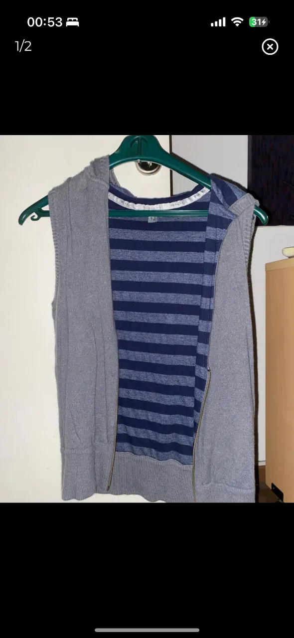 Chaleco reversible de mujer, con capucha y cierre. Un lado es gris liso y el otro a rayas azules y blancas. Ideal para usar en capas.
