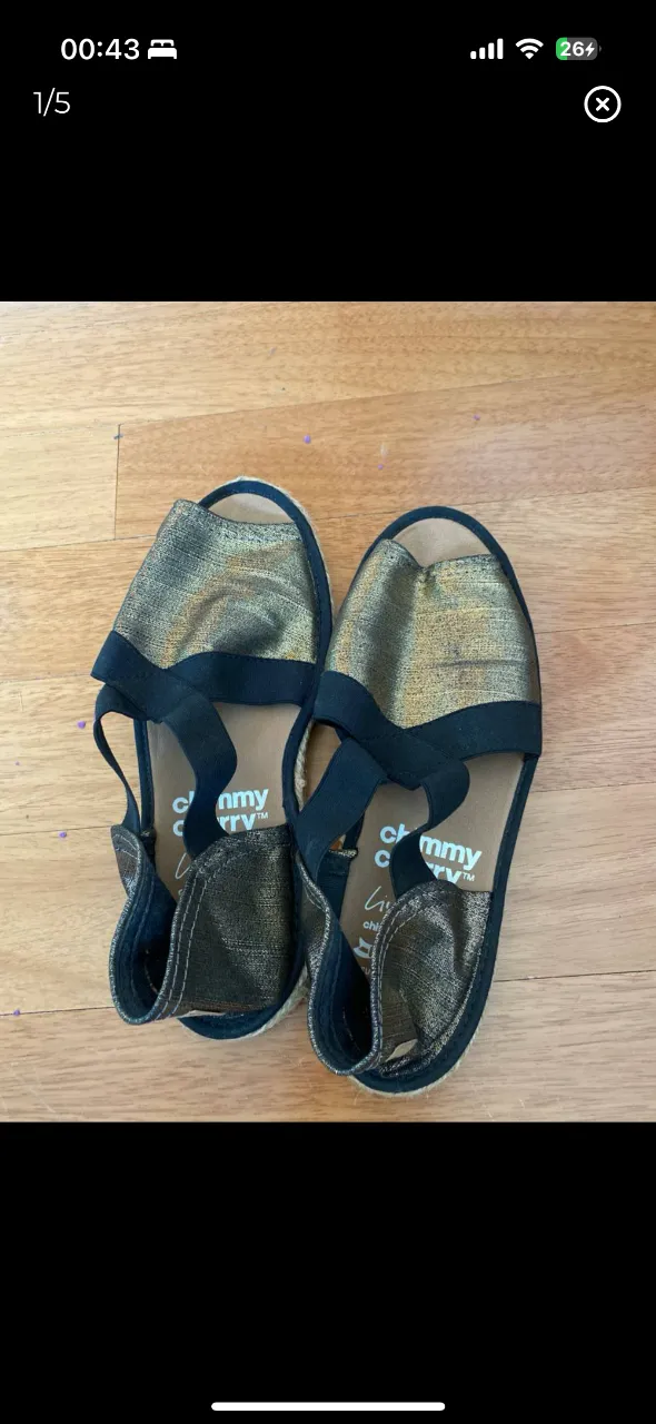 Sandalias doradas con detalles en negro, ideales para un look casual y cómodo. Perfectas para el verano.