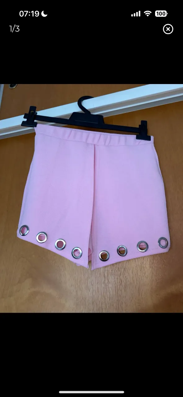 Shorts de mujer tiro alto en color rosa, con detalles de ojales metálicos en los bordes. Ideal para un look moderno y femenino.