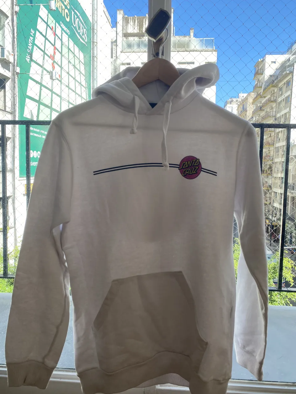 Buzo blanco con capucha y bolsillo canguro. Estampa circular con el logo de Santa Cruz en el frente y en la espalda.