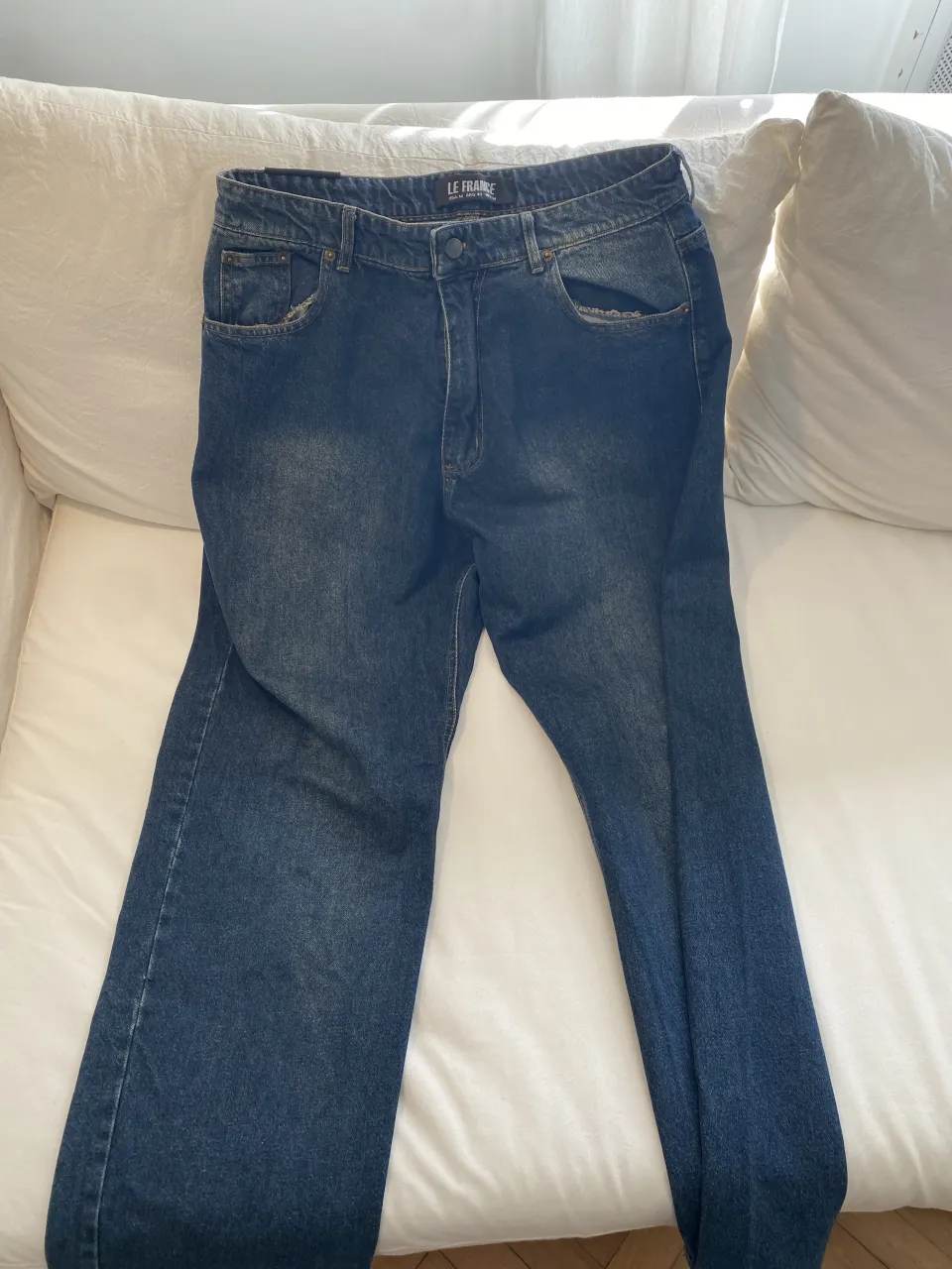 Jeans de corte clásico, color azul oscuro con desgaste leve. Posee bolsillos delanteros y traseros.