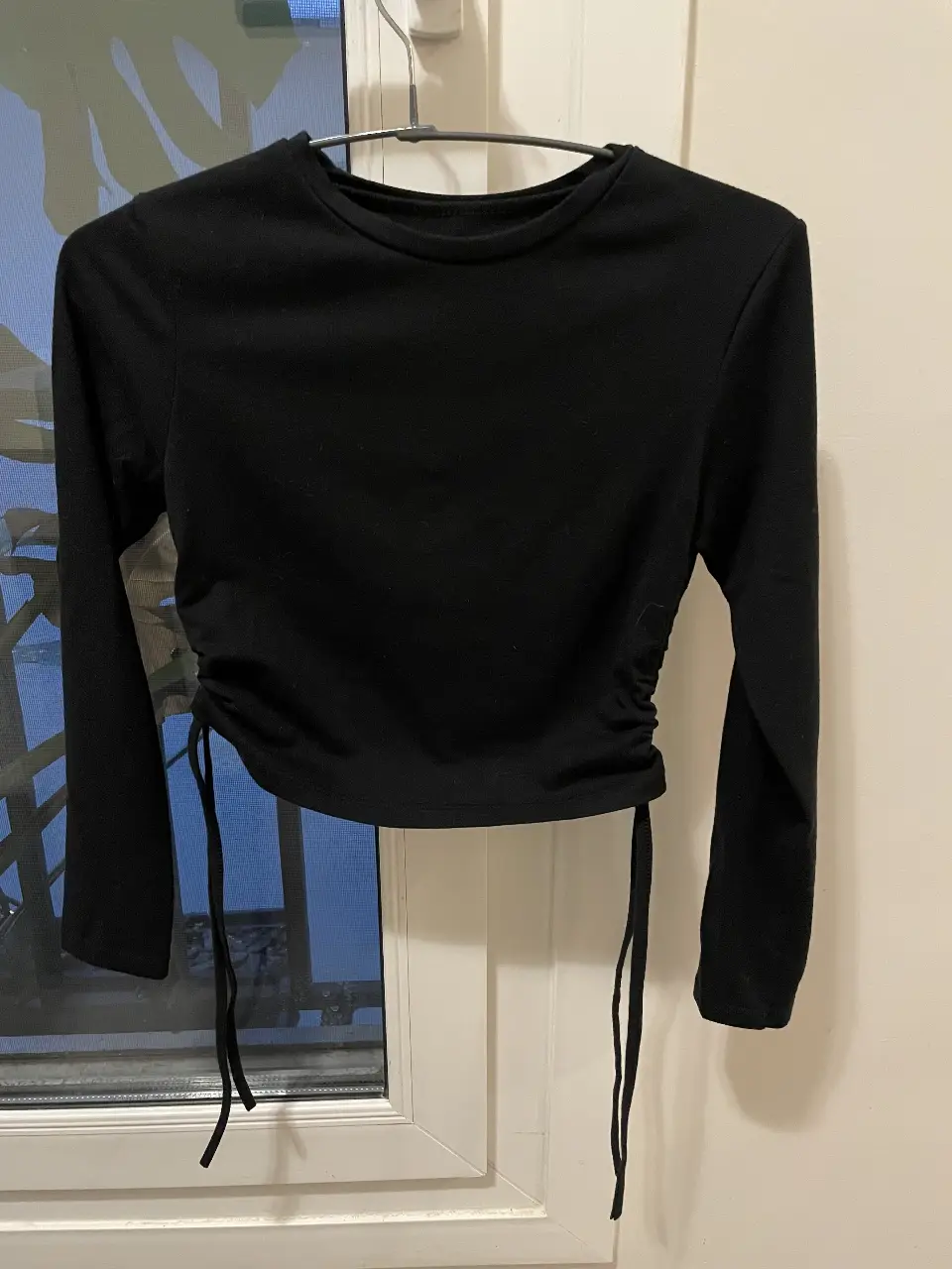 Remera manga larga negra con fruncido lateral. Ideal para un look casual y moderno.