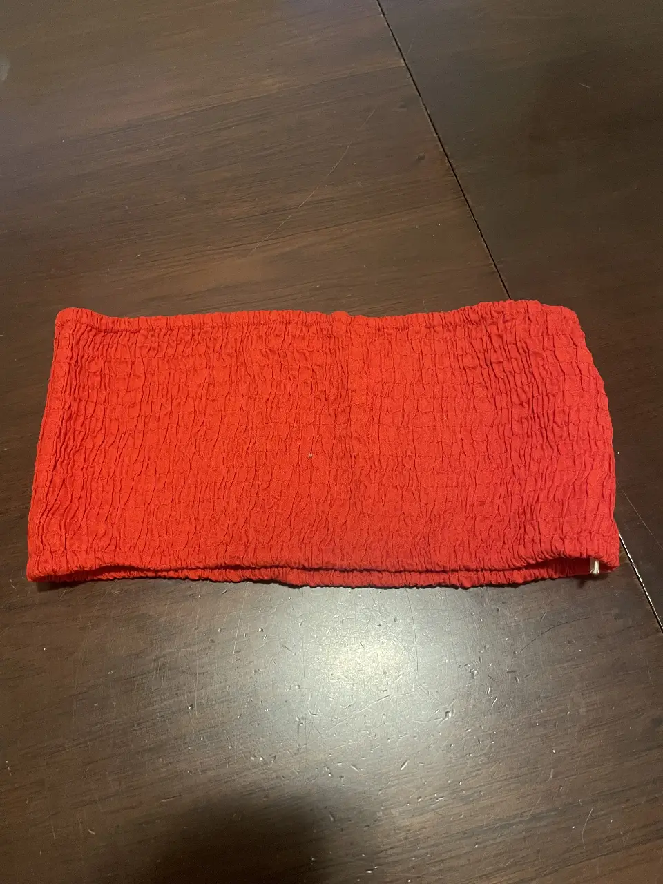 Top strapless rojo con textura arrugada. Ideal para un look moderno y audaz. Perfecto para combinar con jeans o faldas.
