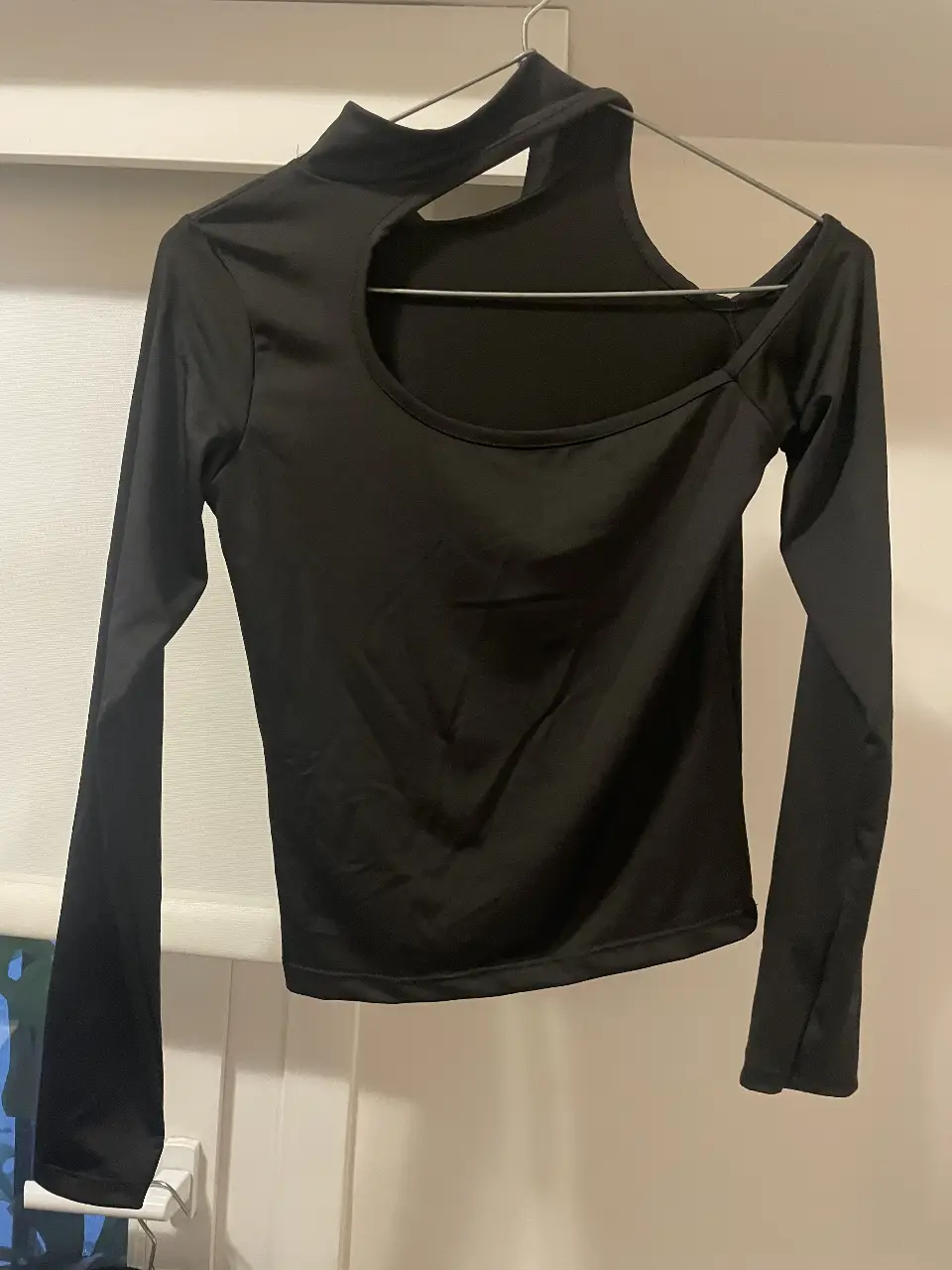 Remera negra de manga larga con diseño asimétrico y cuello alto. Ideal para un look moderno y audaz.