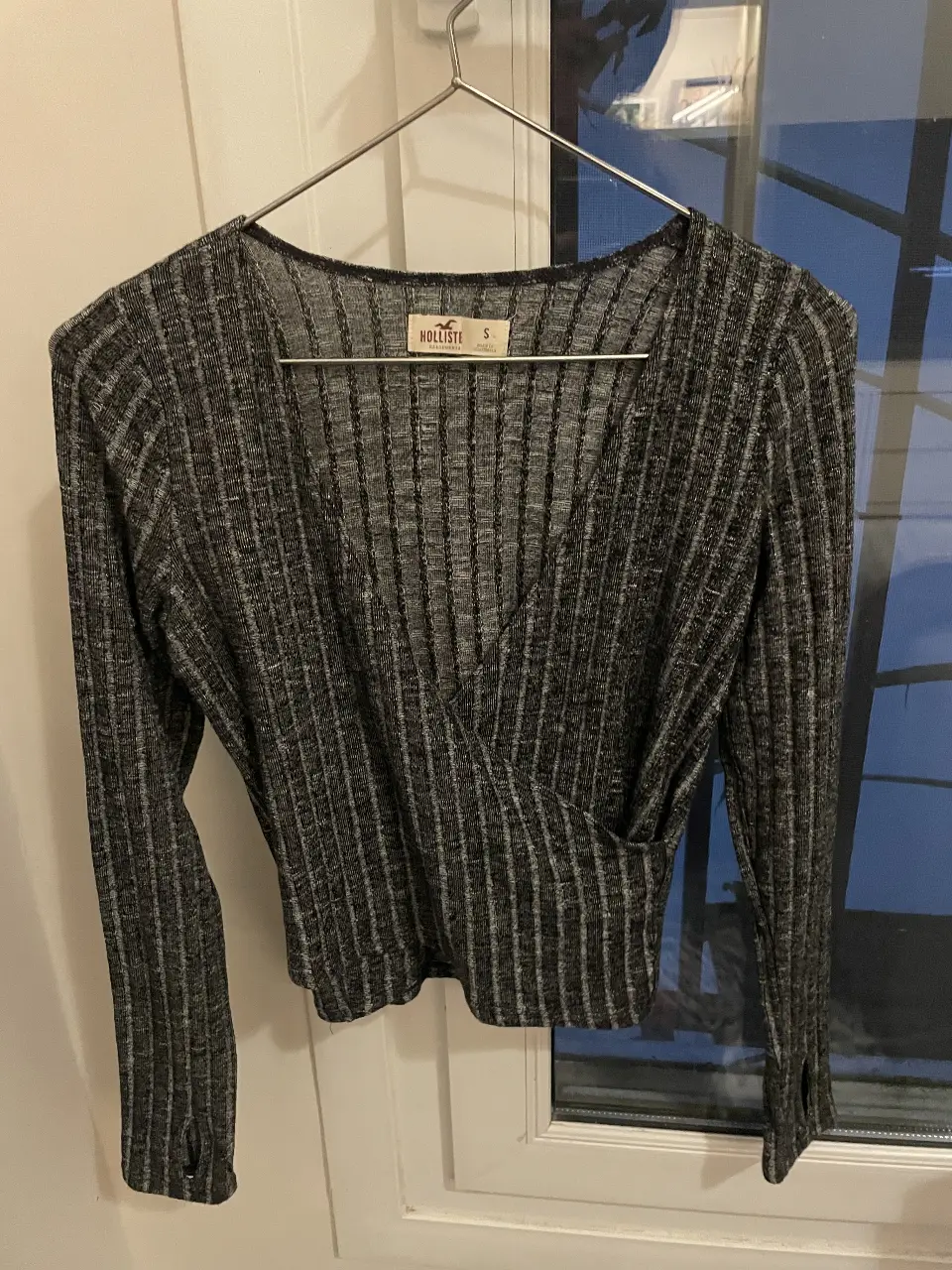 Blusa de manga larga Hollister, con diseño cruzado y textura acanalada. Ideal para un look casual y moderno.
