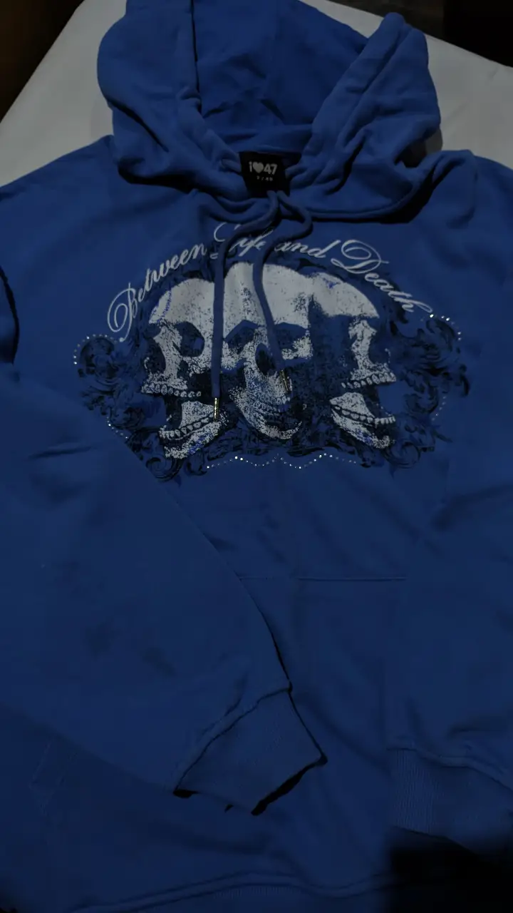 Buzo 47 street canguro azul con estampado de calaveras en blanco.. Diseño con capucha y cordones. Ideal para un look rocker y casual.