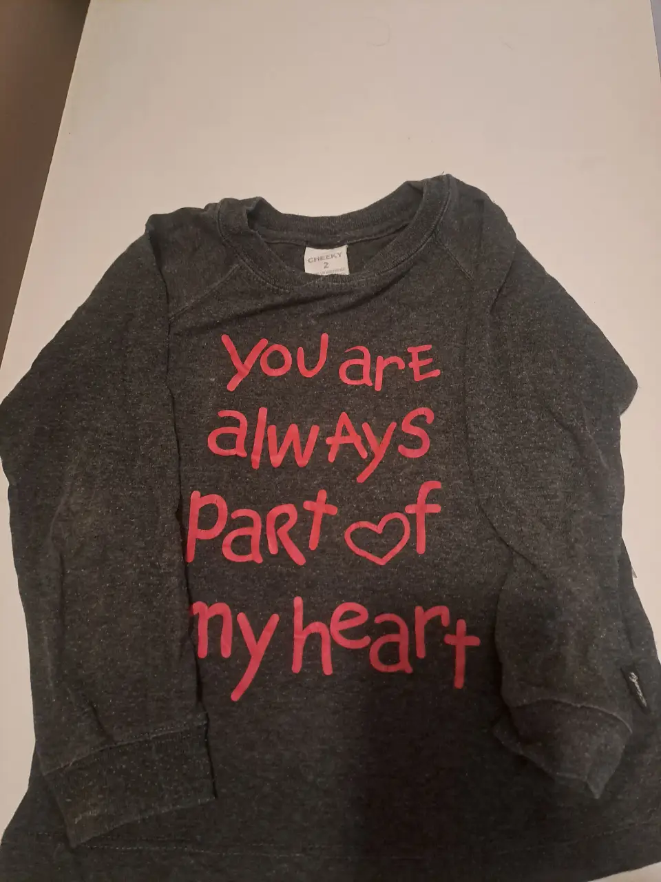 Buzo de cuello redondo para niña, color gris con estampado en rosa. Con la frase "You are always part of my heart". Ideal para un look casual y cómodo.