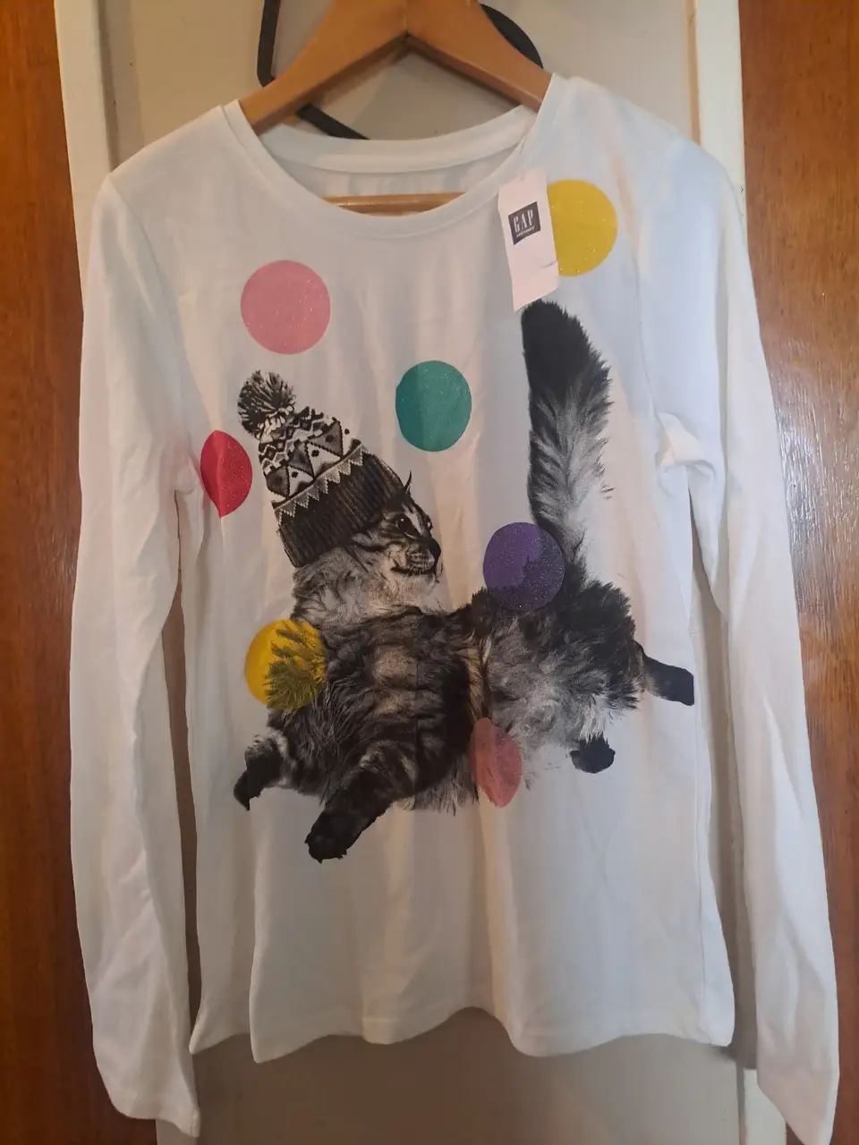 Remera manga larga blanca de niña con estampado de gato con gorro y lunares de colores. Ideal para un look casual y divertido.