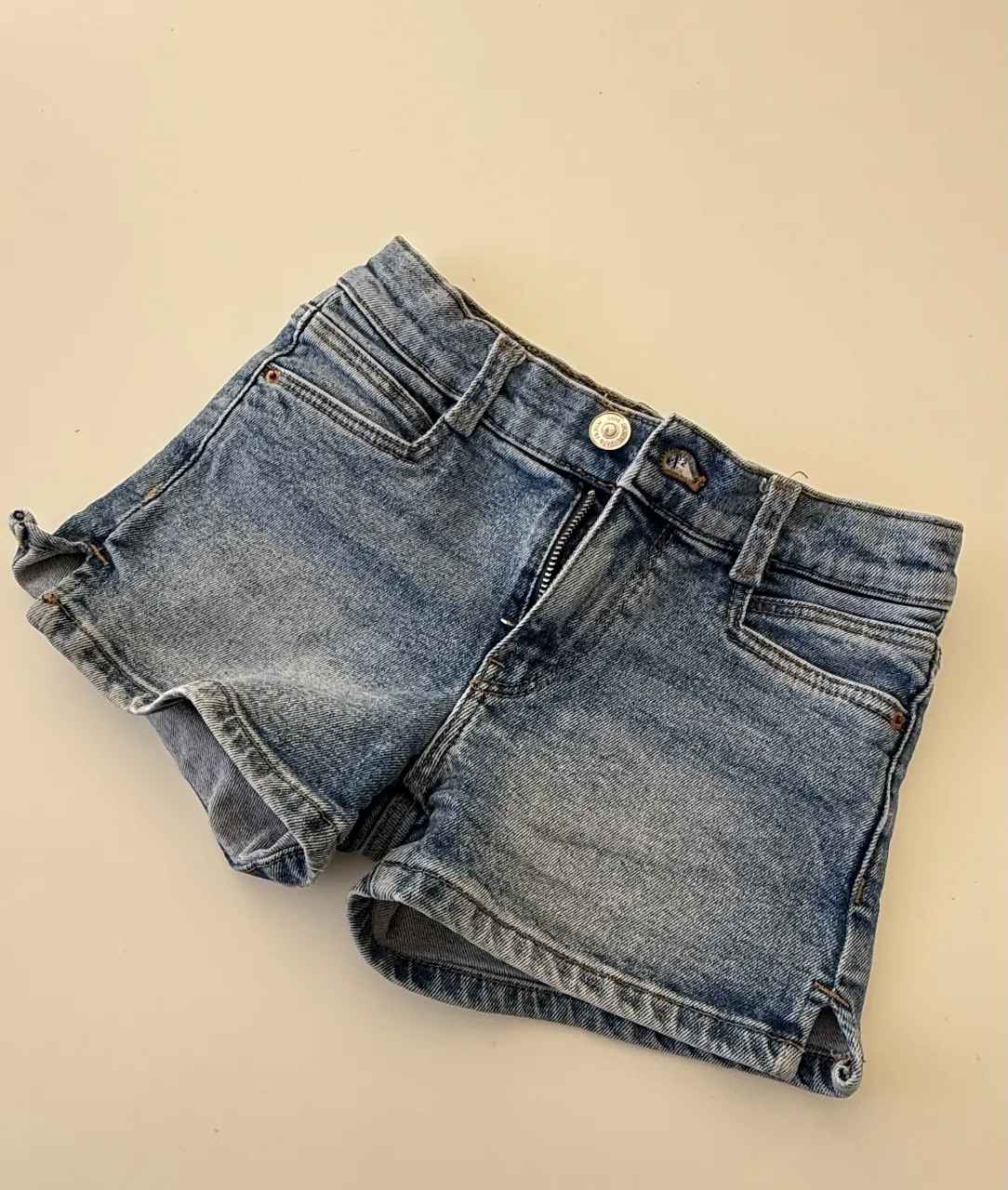 Short de jean azul claro para niña, con detalles de desgaste y cierre frontal. Ideal para un look casual y cómodo.