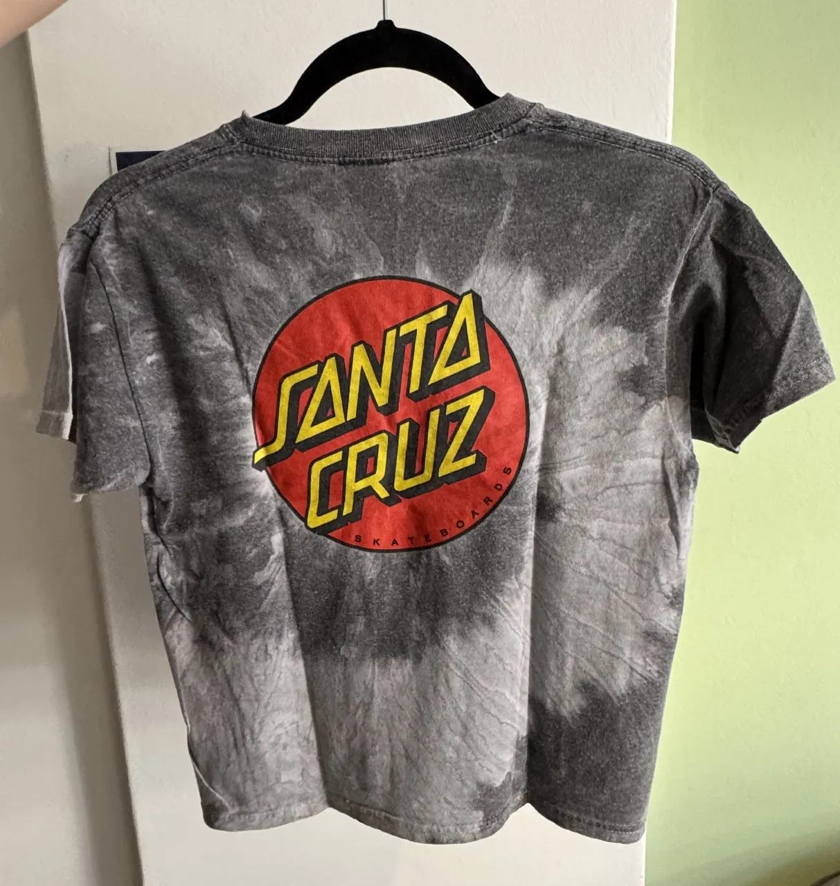 Remera de mujer con diseño tie dye en tonos grises y negros. Presenta el logo de Santa Cruz en el frente. Ideal para un look casual y urbano.