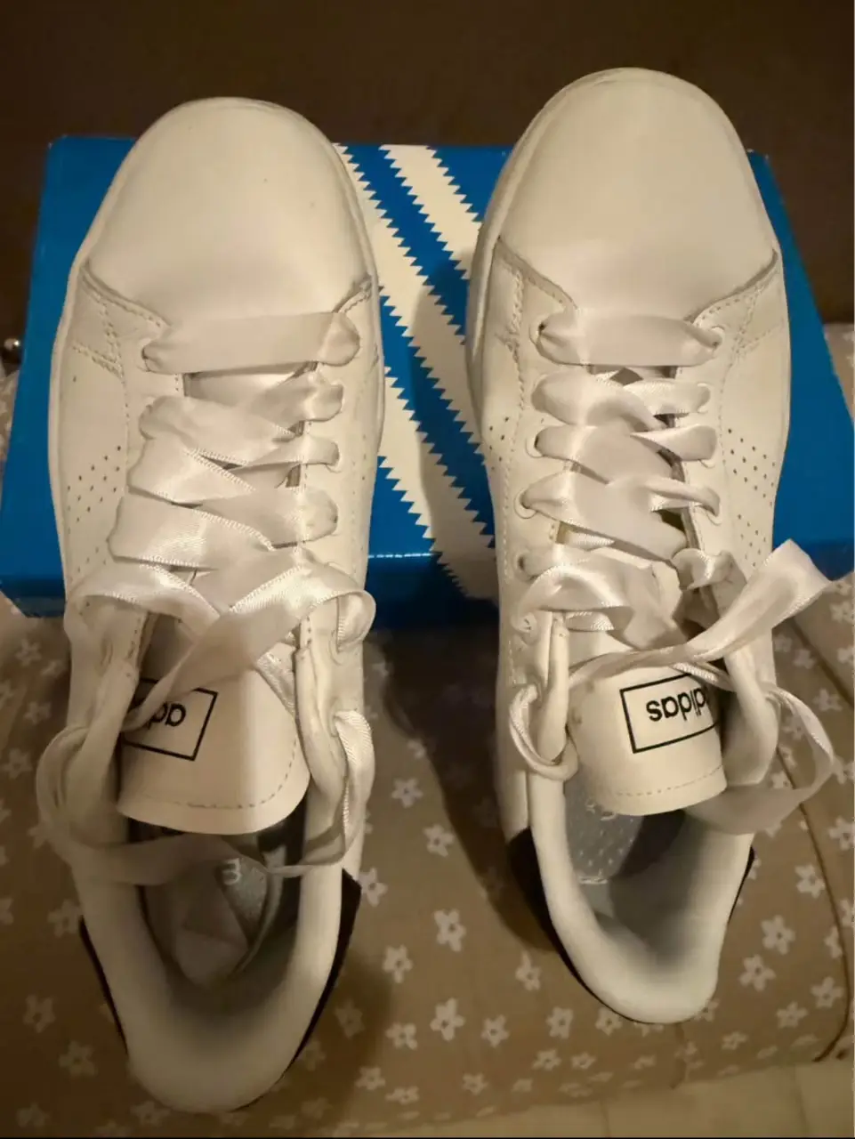 Zapatillas Adidas blancas, con detalles en negro y cordones blancos. Tienen el logo de la marca en la lengüeta y en el lateral. Ideales para un look casual y cómodo.
