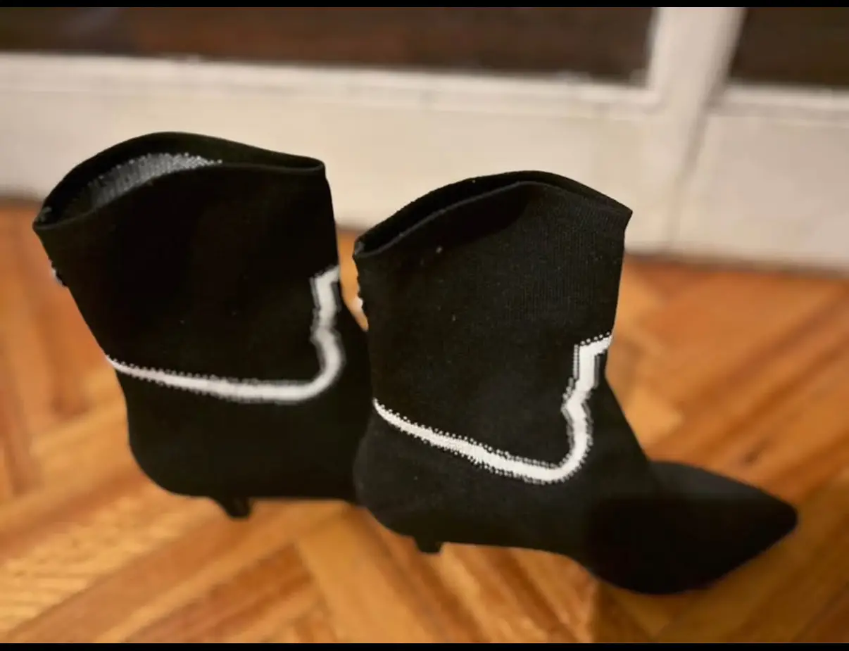 Botines de mujer negros con detalles blancos. Diseño moderno y elegante, ideales para complementar cualquier look. Confeccionados en material de punto elástico, ofrecen comodidad y estilo. Perfectos para diversas ocasiones.