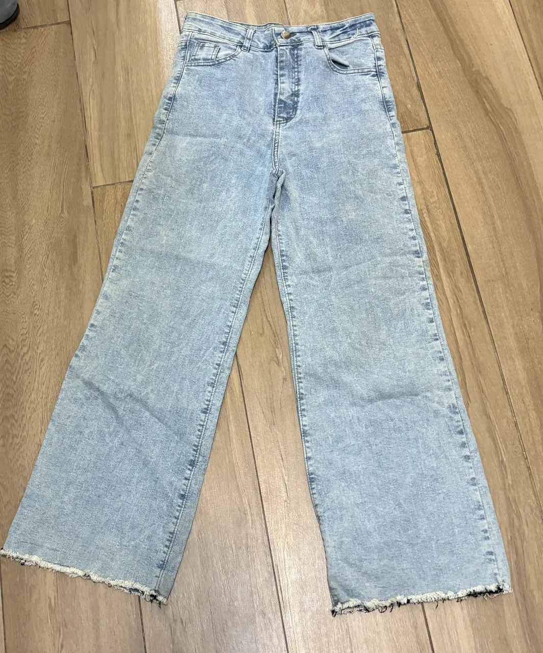 Jean de tiro alto, corte ancho y desflecado en la botamanga. Lavado celeste con efecto desgastado.