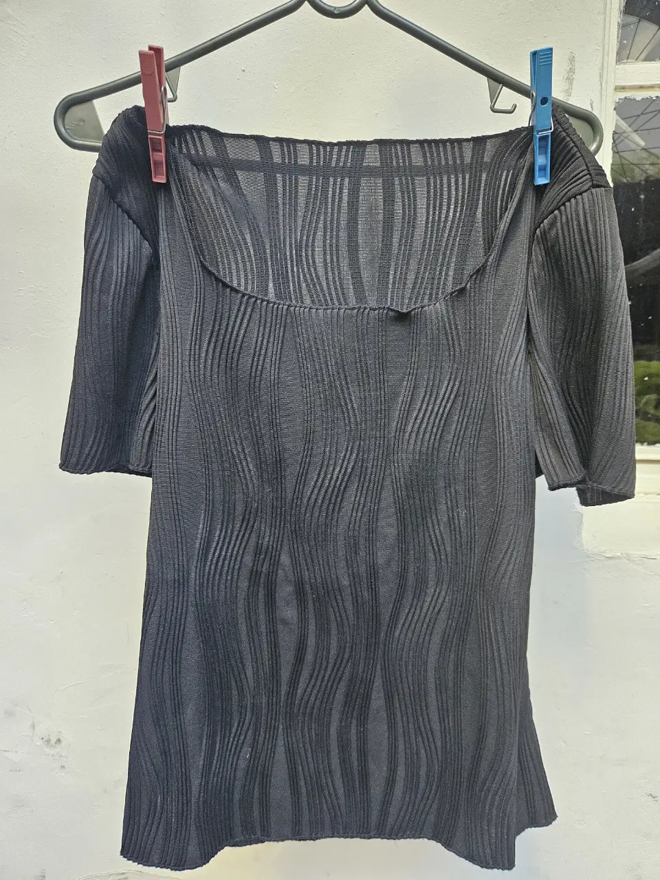 Blusa negra con textura ondulada, ideal para un look elegante y sofisticado. Perfecta para combinar con pantalones de vestir o faldas.