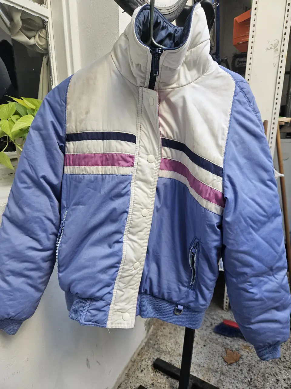 Campera deportiva retro con diseño en bloques de color azul y blanco, con detalles en rosa y azul marino. Ideal para un look vintage y abrigado.