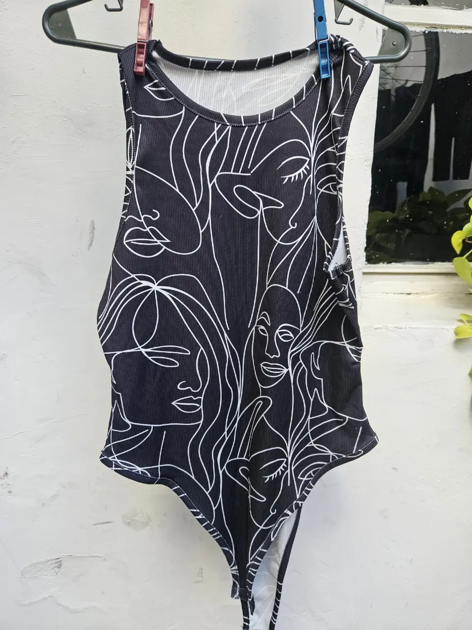 Body negro con estampado de caras blancas. Ideal para un look moderno y audaz. Perfecto para combinar con jeans o faldas.