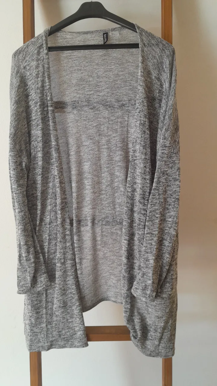 Cardigan de tejido liviano, ideal para usar en días frescos o como una capa adicional. Su diseño abierto y su textura jaspeada lo hacen versátil y cómodo.