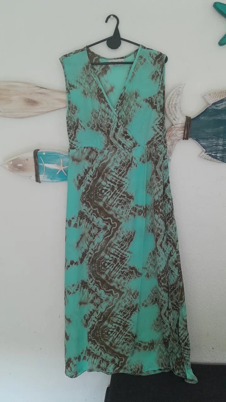 Vestido largo estampado en tonos turquesa y marrón. Posee escote cruzado en V y es sin mangas.