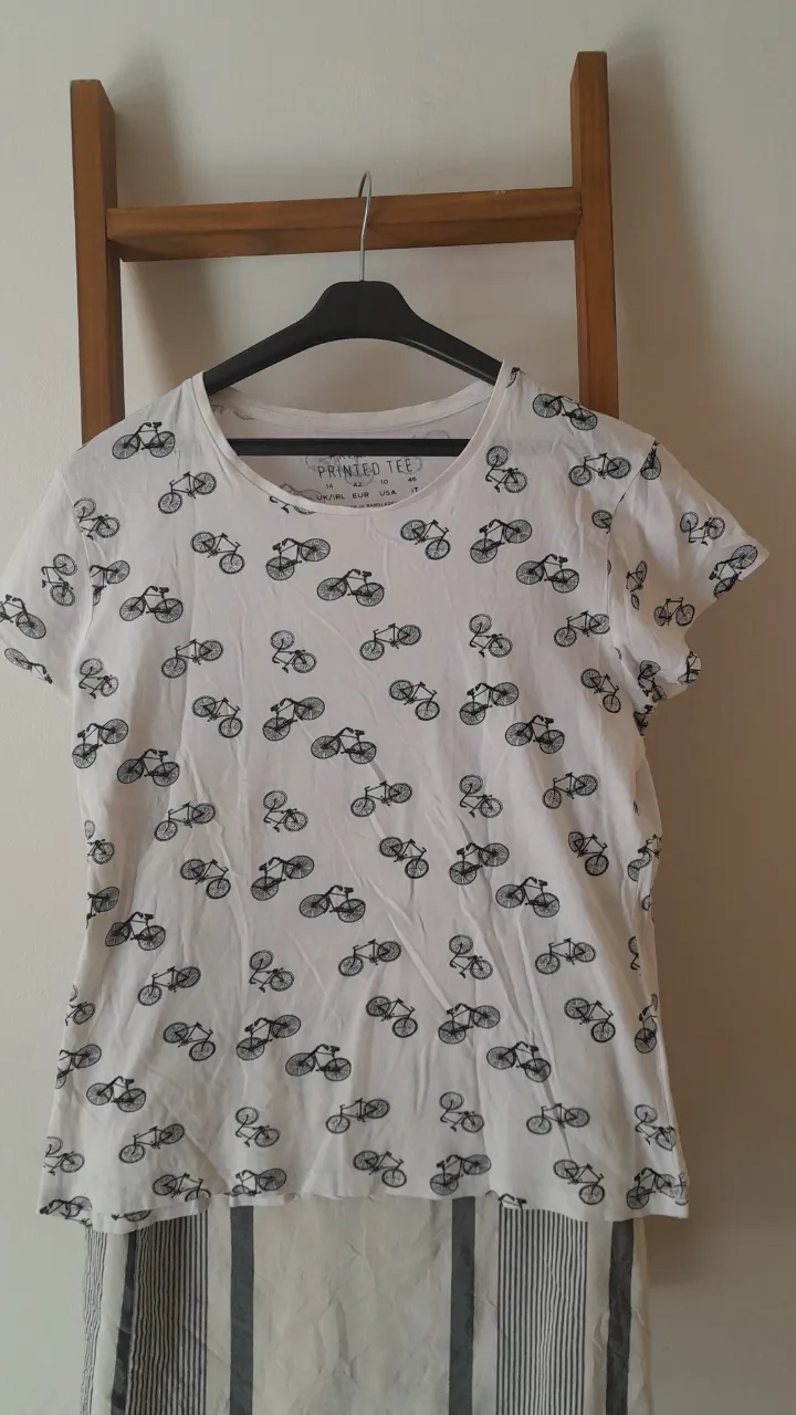 Remera blanca con estampa de bicicletas en negro. Es cómoda y canchera, ideal para el día a día. Queda genial con jeans o shorts.