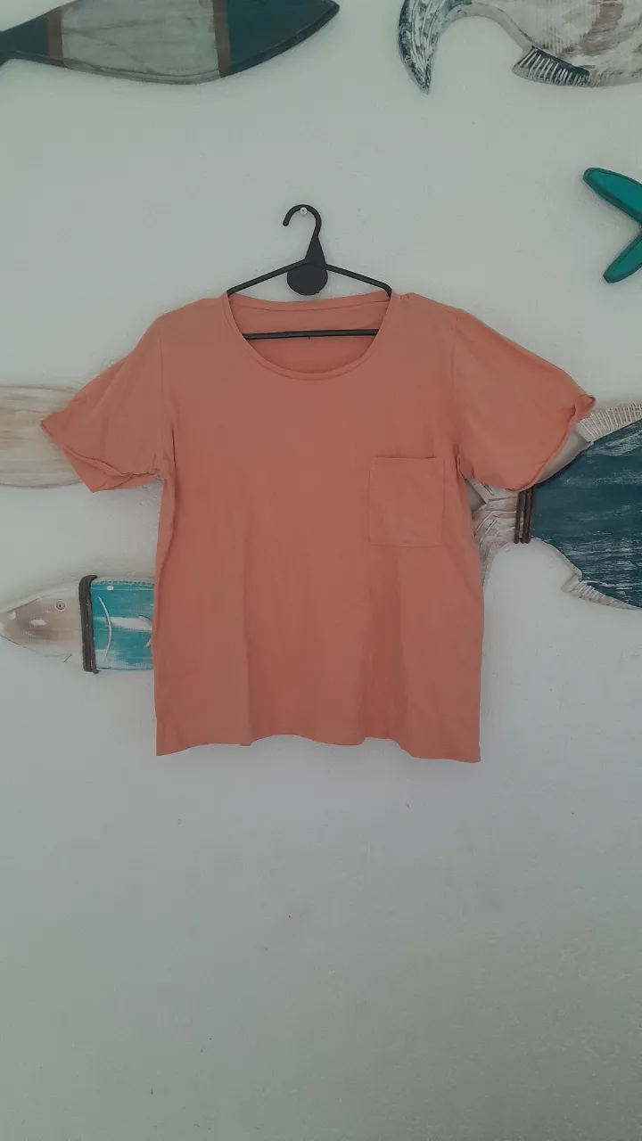 Remera de manga corta color salmón con bolsillo en el frente.