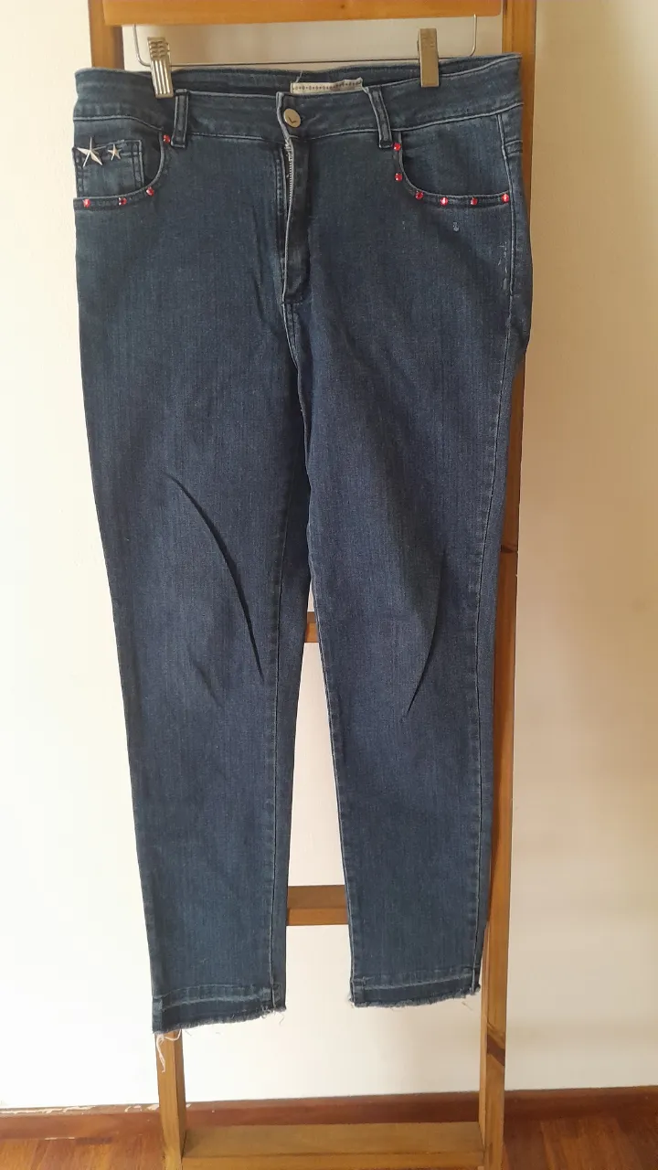 Jeans tiro alto con detalles de strass en los bolsillos delanteros y traseros. Diseño con roturas sutiles en los bajos y un corte moderno que los hace perfectos para cualquier ocasión.