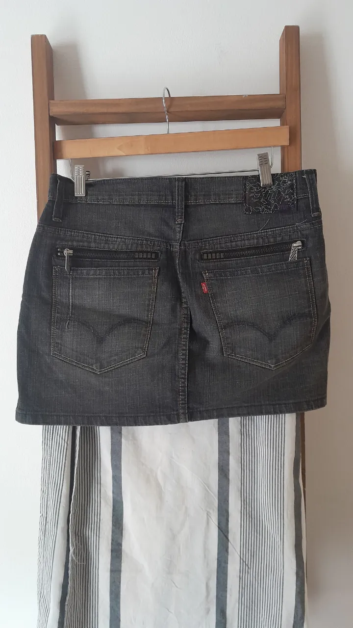 Pollera de jean gris oscuro, tiro alto, con bolsillos delanteros y traseros con cierre. Un clásico que no puede faltar en tu guardarropa.