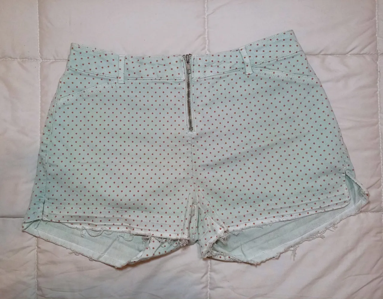 Shorts de jean tiro alto con estampa de lunares. Cierre metálico al frente y detalles desflecados en los bordes. Talle 40/42