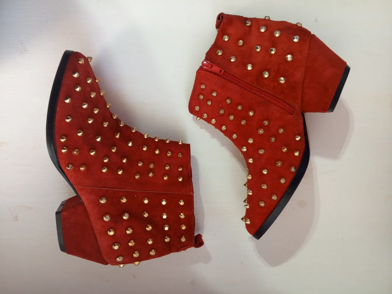 Botines rojos de gamuza con tachas doradas. Tienen cierre lateral y taco ancho. Ideales para darle un toque rocker a tu look.