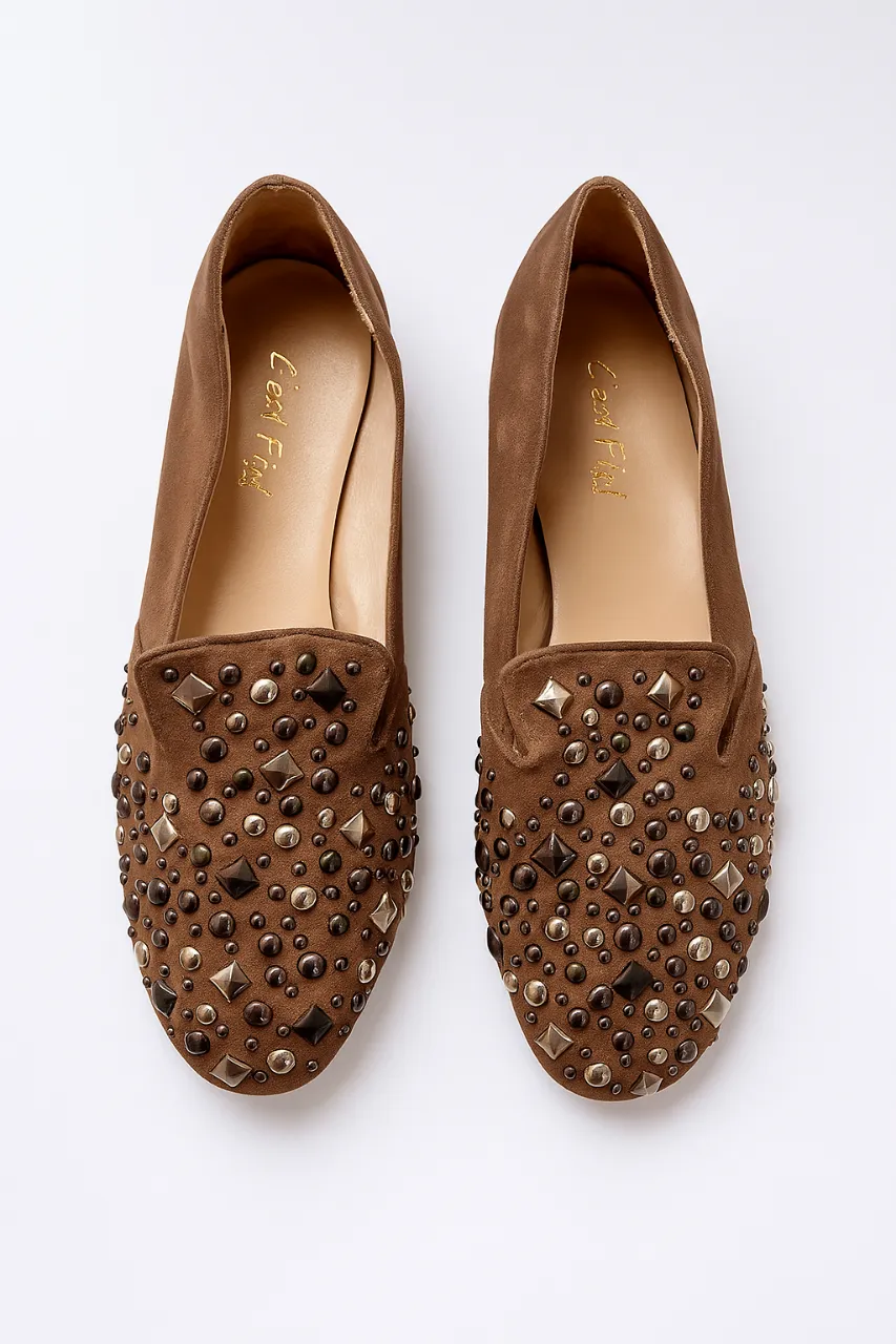 Mocasines marrones de gamuza con detalles de tachas en la puntera. Ideales para un look casual y cómodo.
