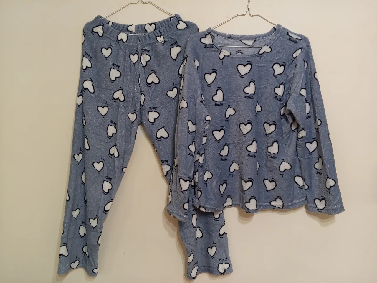 Pijama de dos piezas para mujer, con estampado de corazones blancos sobre fondo azul. Incluye pantalón largo y remera de manga larga, ideal para el descanso y el confort.