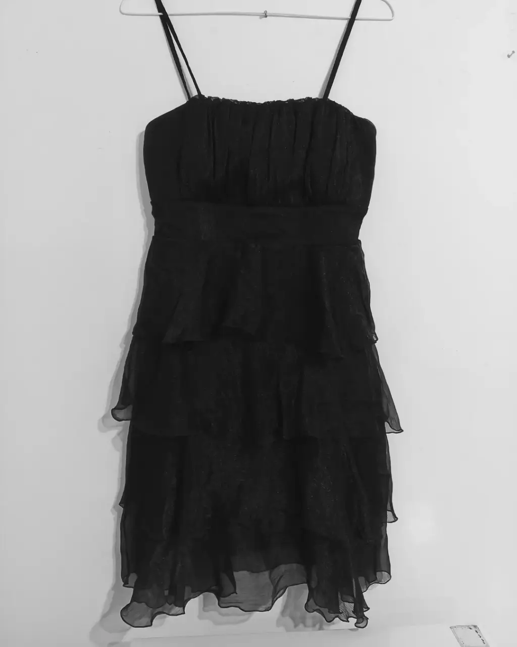 Vestido negro corto con tirantes finos y detalles de volantes. Ideal para fiestas y eventos especiales.
