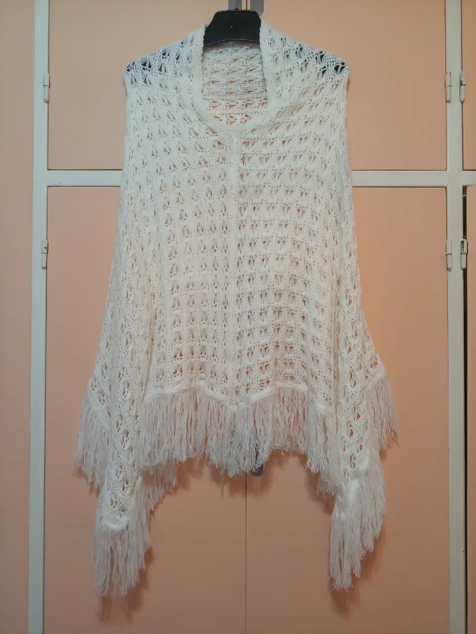 Poncho tejido a crochet en color blanco, con flecos en el borde inferior. Ideal para un look bohemio y elegante.
