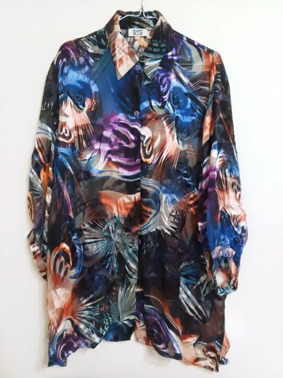Camisa estampada de manga larga con diseño abstracto en tonos azules, violetas y naranjas. Ideal para un look moderno y llamativo.