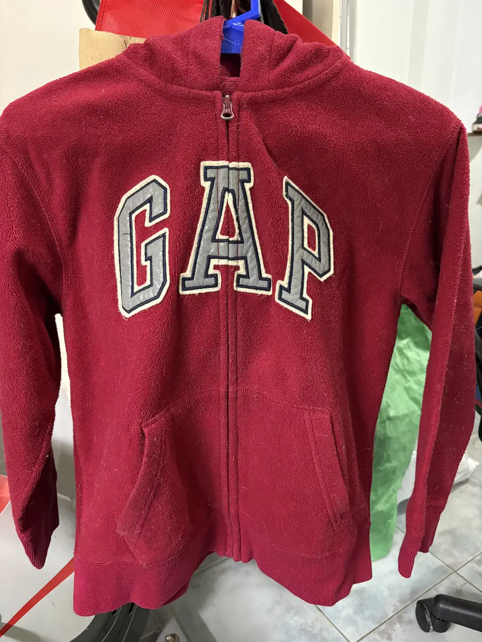 Buzo con cierre de la marca GapKids, color rojo, con el logo "GAP" en el frente. Talle L (10). Ideal para un look casual y abrigado.
