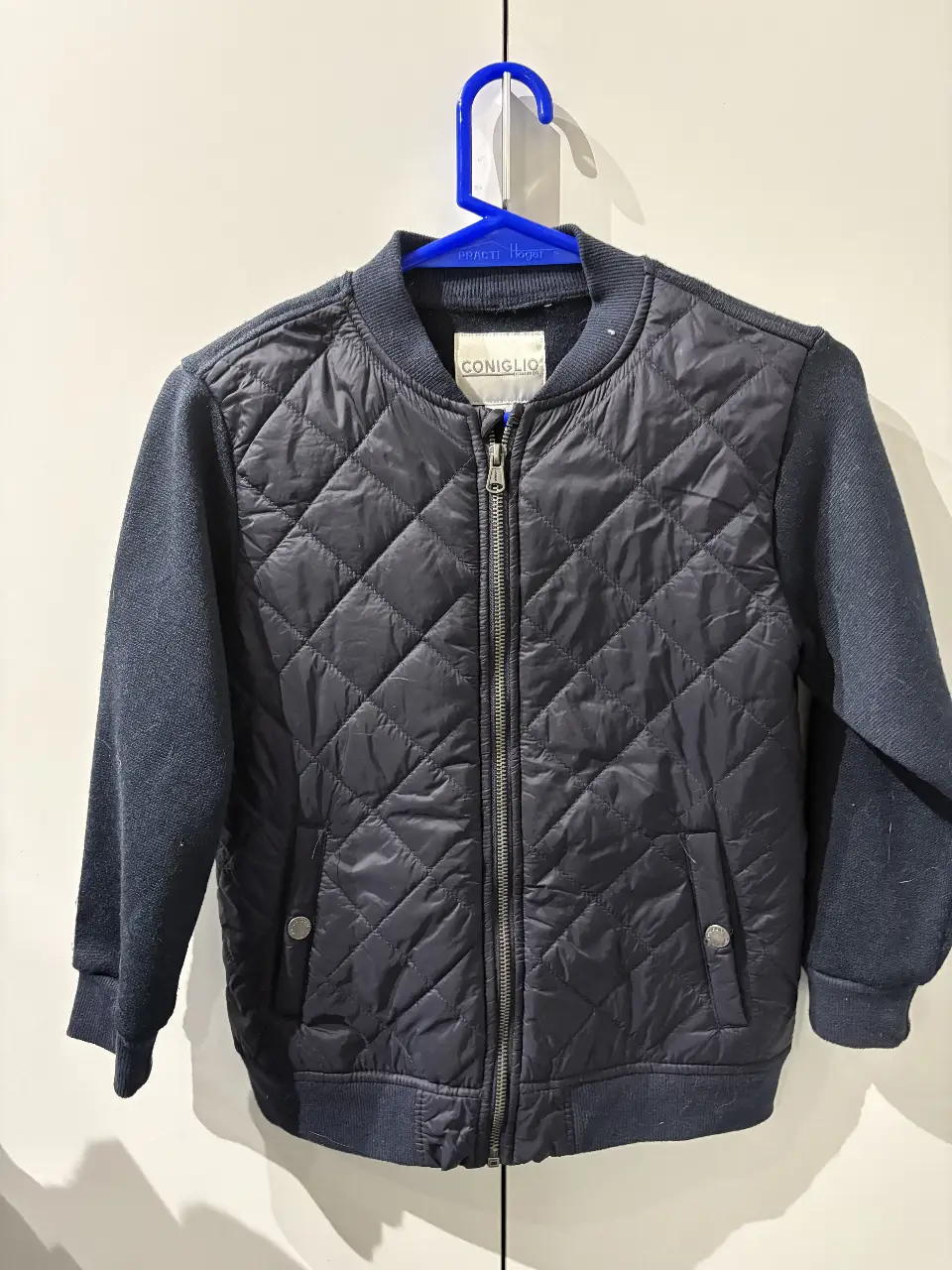 Campera bomber para niño, color azul marino con mangas en tejido de punto. Diseño acolchado en el cuerpo y cierre frontal. Ideal para el invierno.