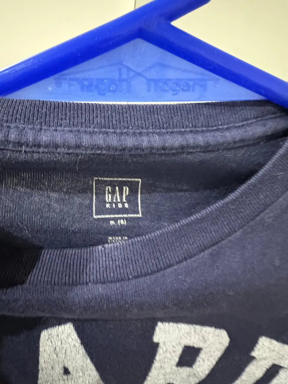 Remera manga larga azul marino para niño con estampado "HARD COURT 25" en blanco y naranja. Diseño deportivo con mangas grises.