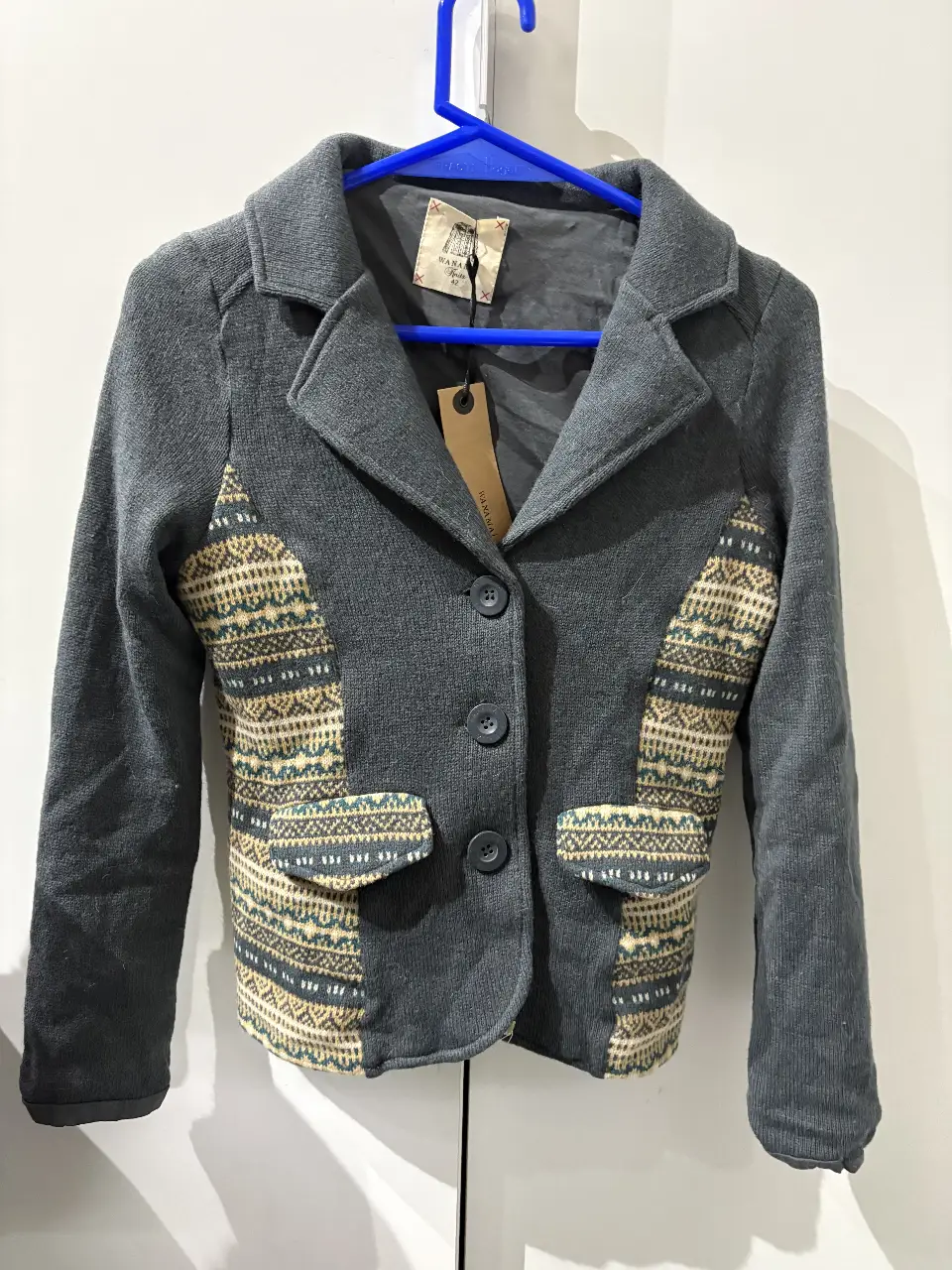 Chaqueta blazer gris con detalles en tela estampada en los laterales y bolsillos. Ideal para un look casual y moderno.