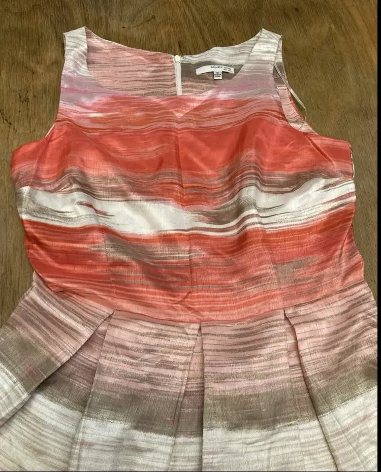 Vestido midi de Studio One New York, con estampado abstracto en tonos naranja, blanco y marrón. Corte a la cintura con falda plisada, ideal para un look elegante y moderno.