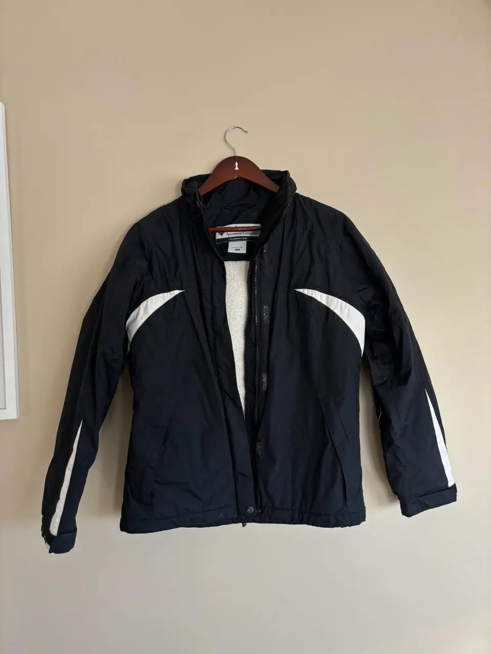 Campera deportiva Columbia negra con detalles blancos. Ideal para actividades al aire libre y climas fríos. Posee cierre frontal y detalles en blanco en mangas y laterales. Interior con abrigo.