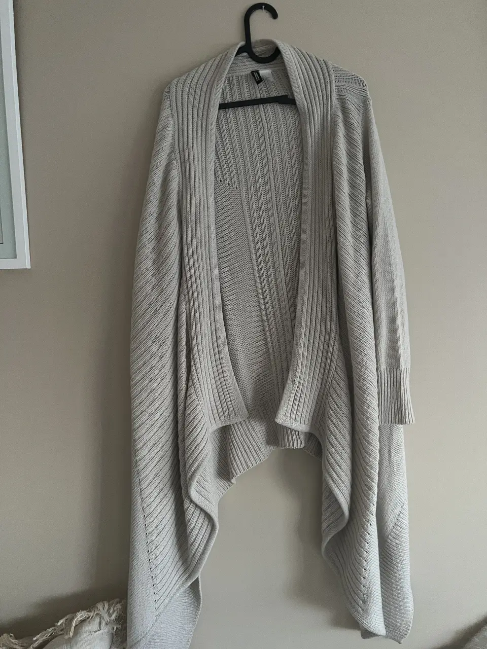 Cardigan de mujer, color gris claro, con diseño asimétrico y tejido de punto. Ideal para un look casual y cómodo.
