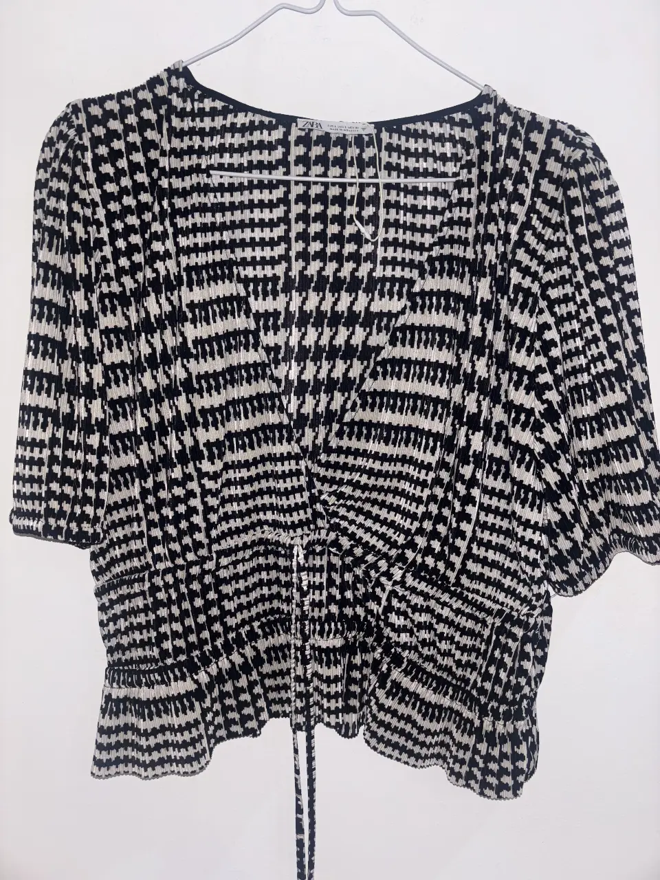 Blusa de mujer con estampado geométrico en blanco y negro. Diseño con fruncido en la cintura y mangas cortas. Ideal para un look casual y moderno.
